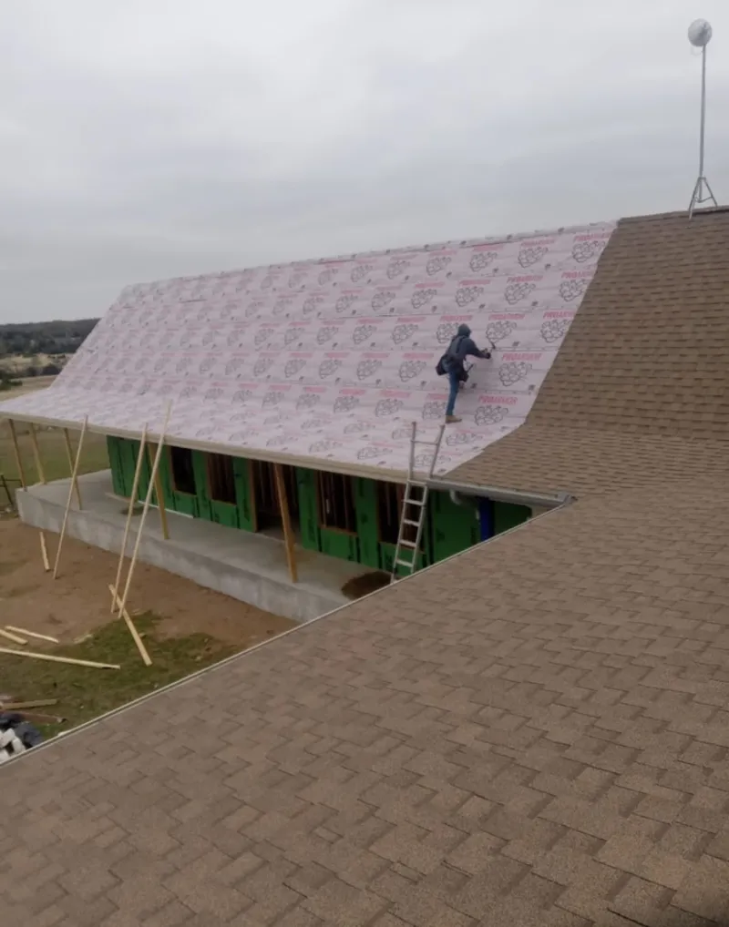 Worker preparing underlayment for a metal roof installation in Cumru